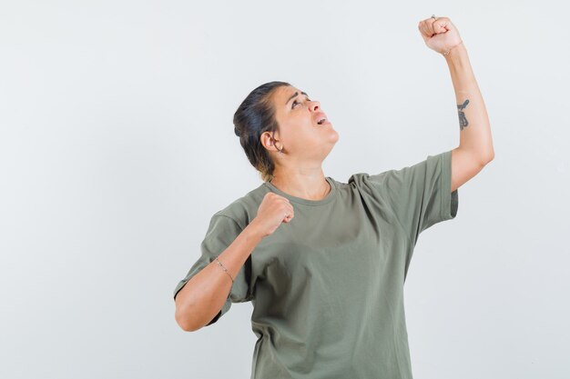 mujer en camiseta mostrando gesto ganador y mirando dichoso