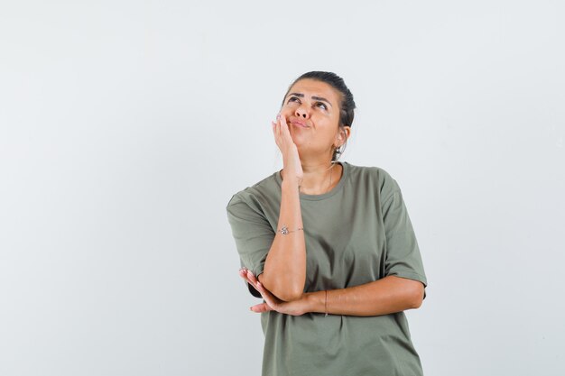 Mujer en camiseta de pie en pose de pensamiento y mirando indeciso