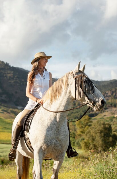 Mujer campesina sonriente paseos a caballo en la naturaleza