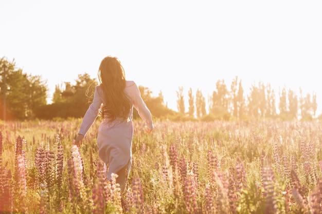 Mujer en el campo de flor de la puesta del sol.