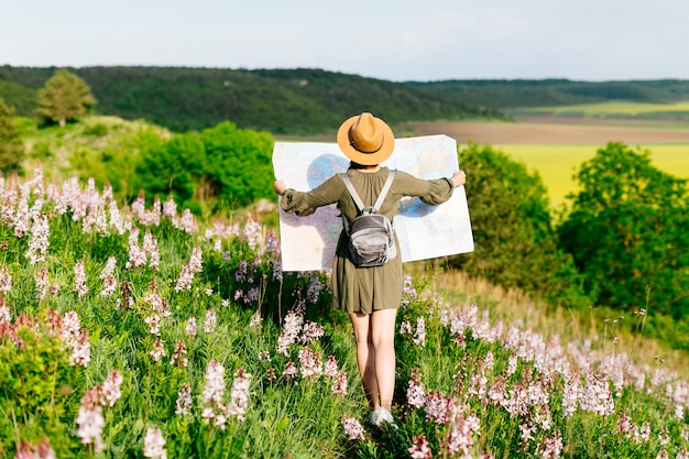 Mujer en campo mirando a mapa grande