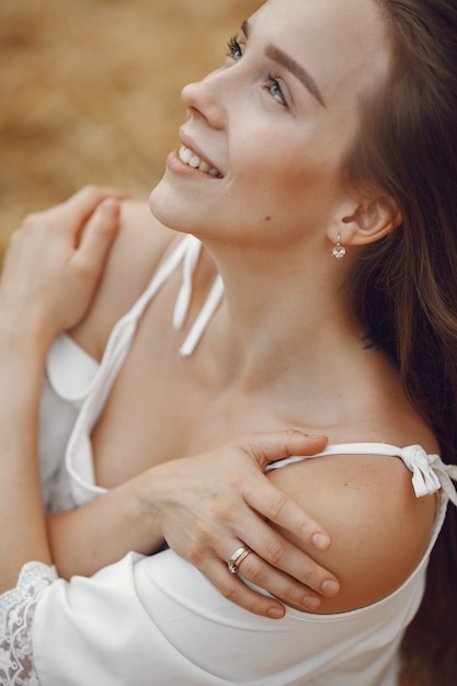 Mujer en un campo de verano. Dama con un vestido blanco.