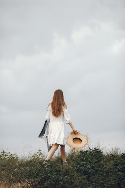 Mujer en un campo de verano. Dama con un vestido blanco.