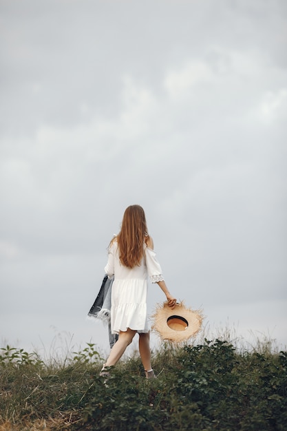 Mujer en un campo de verano. Dama con un vestido blanco.