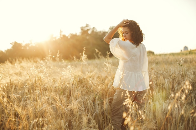 Mujer en un campo de verano. Morena con camisa blanca.