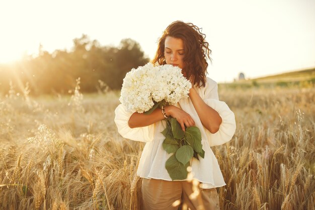 Mujer en un campo de verano. Morena con camisa blanca.