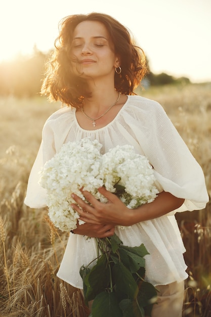 Mujer en un campo de verano. Morena con camisa blanca.