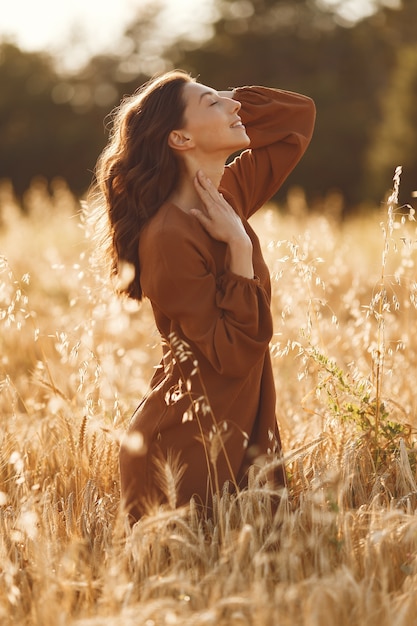 Mujer en un campo de verano. Morena con un suéter marrón.