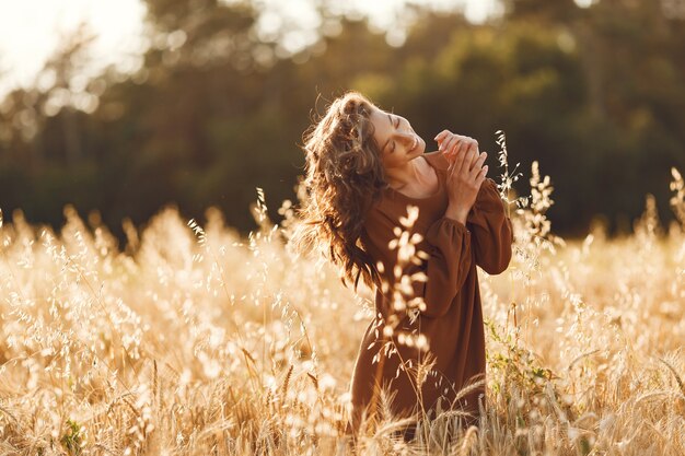 Mujer en un campo de verano. Morena con un suéter marrón.