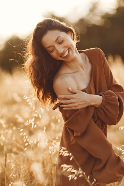 Mujer en un campo de verano. Morena con un suéter marrón.