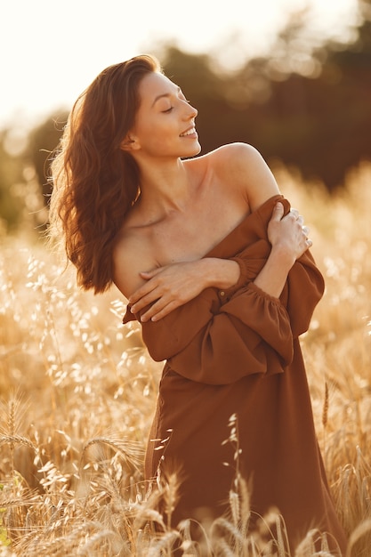 Mujer en un campo de verano. Morena con un suéter marrón.