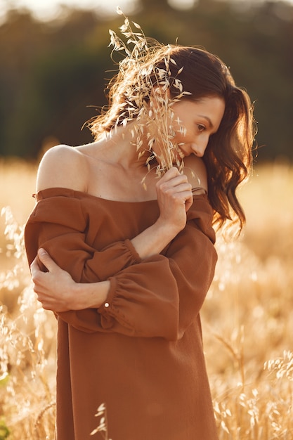 Mujer en un campo de verano. Morena con un suéter marrón.