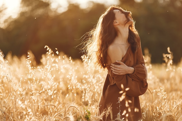 Mujer en un campo de verano. Morena con un suéter marrón.