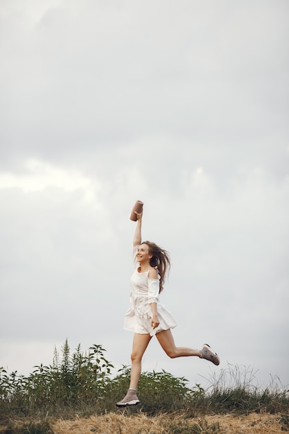 Mujer en un campo de verano. Morena con un vestido blanco. Chica con altavoz de música.