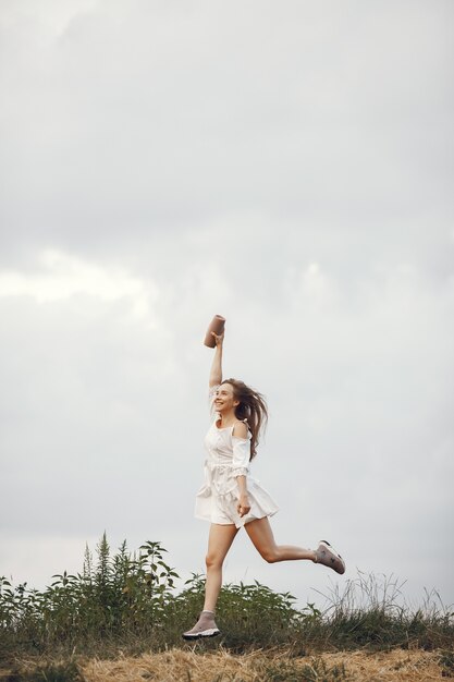 Mujer en un campo de verano. Morena con un vestido blanco. Chica con altavoz de música.