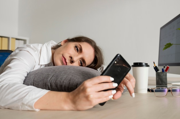 Foto gratuita mujer cansada comprobando el teléfono en el trabajo