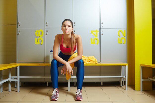 Mujer cansada en habitación de taquillas