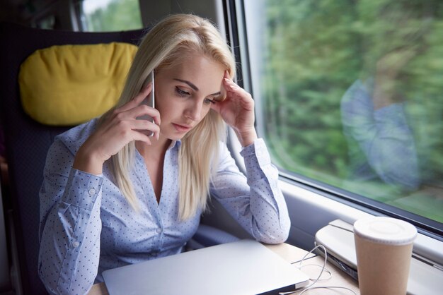 Mujer cansada hablando por teléfono móvil durante el viaje