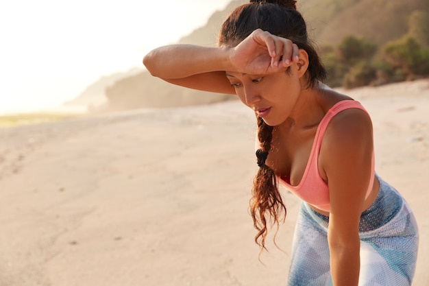 Mujer cansada se limpia la frente después de un intenso entrenamiento físico