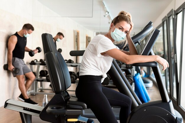 Mujer cansada con máscara médica en el gimnasio