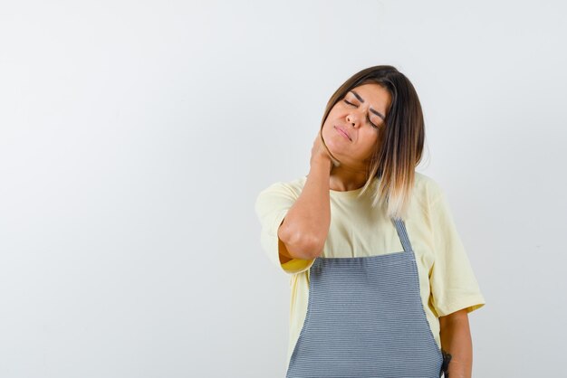 Mujer cansada sosteniendo su cuello con las manos sobre fondo blanco.