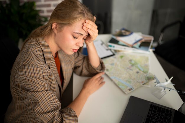 Mujer cansada de tiro medio en agencia de viajes