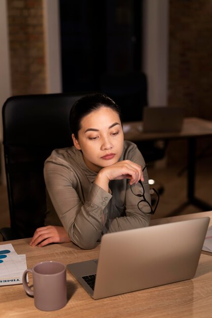 Mujer cansada trabajando hasta tarde en la oficina