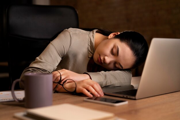 Mujer cansada trabajando hasta tarde en la oficina