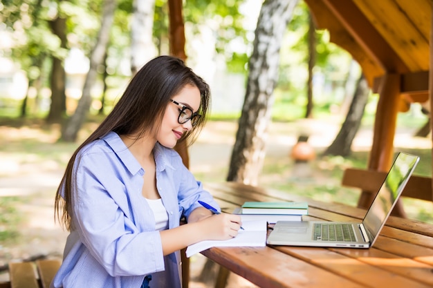 Mujer cansada usando una computadora portátil en una mesa del parque al final del día