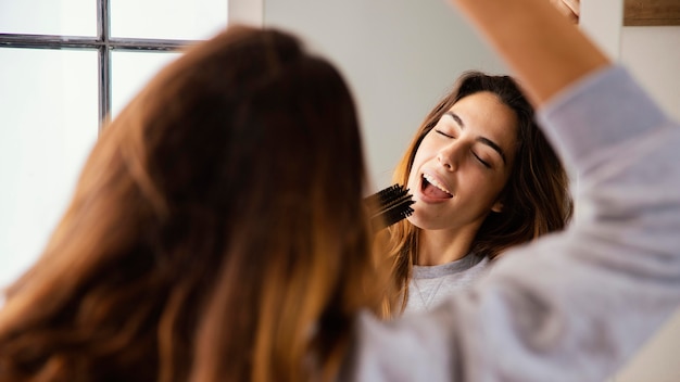 Mujer cantando en cepillo para el pelo en casa