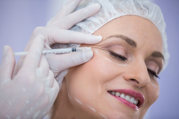 Mujer con cara marcada recibiendo inyección de botox