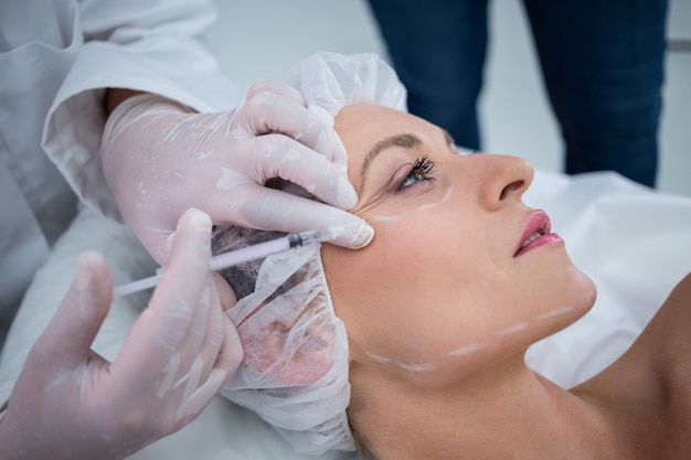 Mujer con cara marcada recibiendo inyección de botox