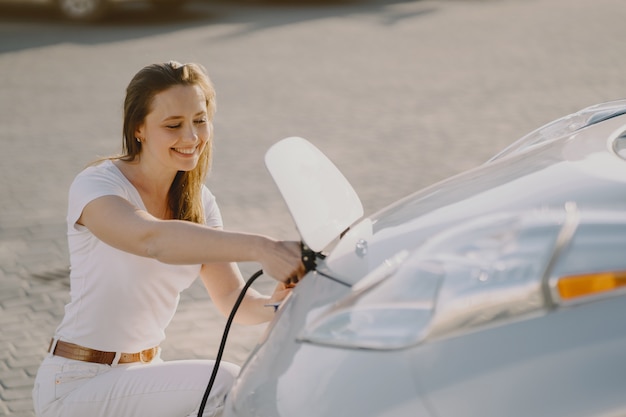 Mujer carga electro car en la gasolinera eléctrica