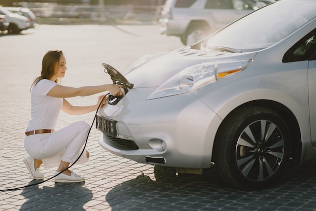 Mujer carga electro car en la gasolinera eléctrica