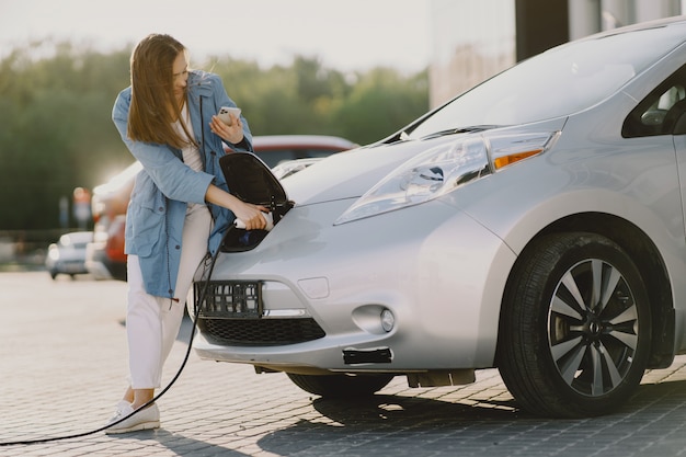 Mujer carga electro car en la gasolinera eléctrica