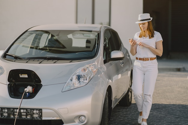 Mujer carga electro car en la gasolinera eléctrica