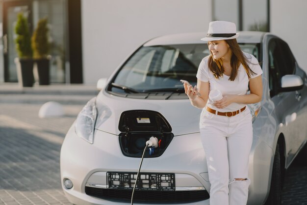 Mujer carga electro car en la gasolinera eléctrica