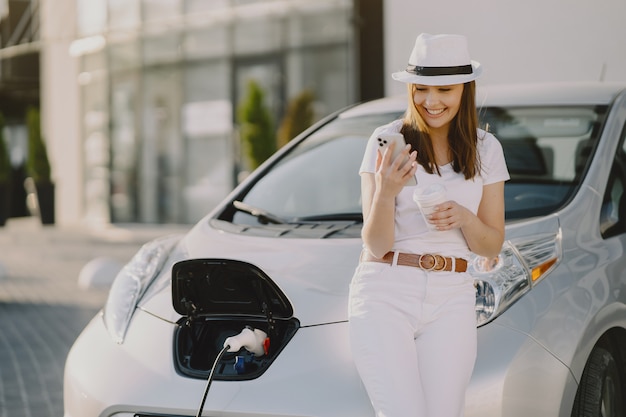 Mujer carga electro car en la gasolinera eléctrica