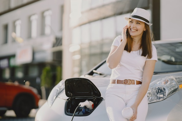 Foto gratuita mujer carga electro car en la gasolinera eléctrica