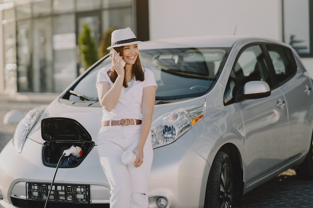 Mujer carga electro car en la gasolinera eléctrica