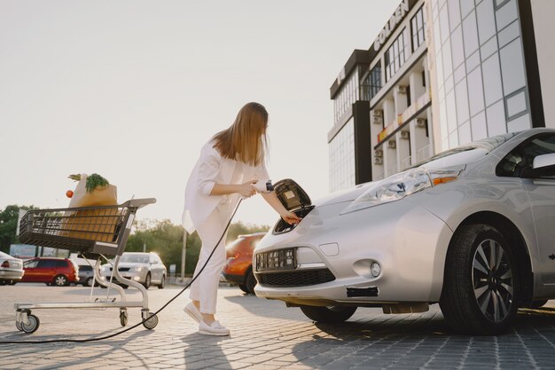 Mujer carga electro car en la gasolinera eléctrica