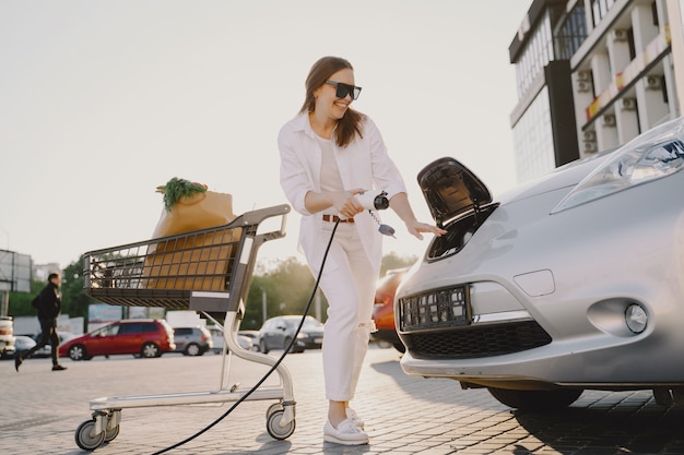 Mujer carga electro car en la gasolinera eléctrica