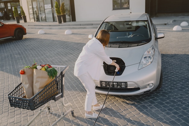 Mujer carga electro car en la gasolinera eléctrica