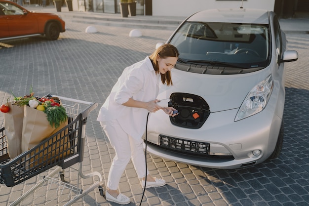 Mujer carga electro car en la gasolinera eléctrica