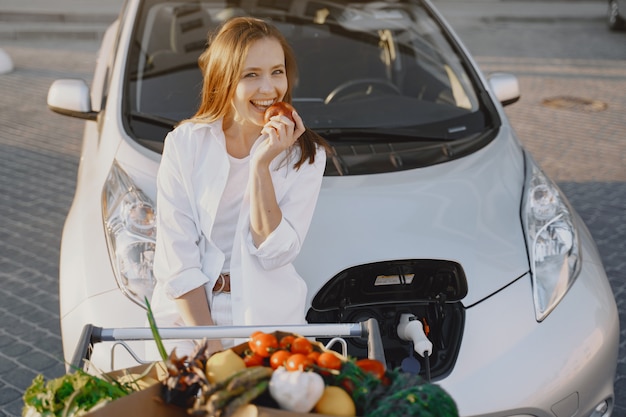 Mujer carga electro car en la gasolinera eléctrica