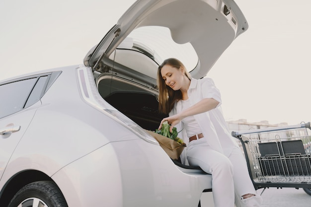 Mujer carga electro car en la gasolinera eléctrica