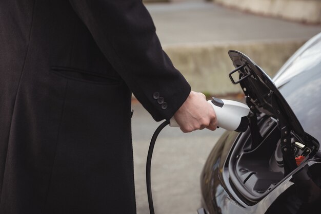 Mujer cargando coche eléctrico en la estación de carga de vehículos eléctricos