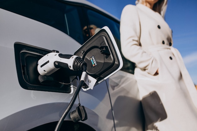 Mujer cargando electro car por su casa