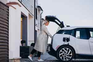 Foto gratuita mujer cargando electro car por su casa