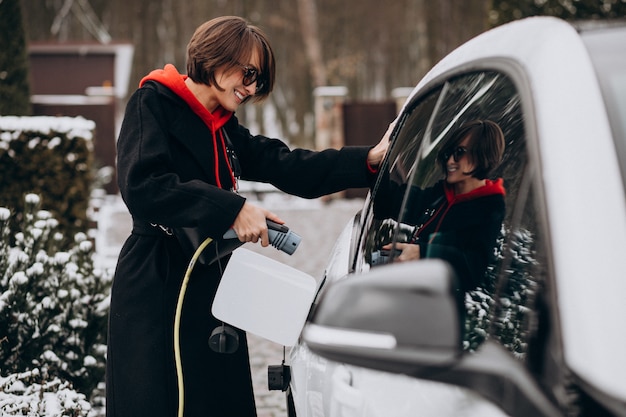 Mujer cargando electro car por su casa